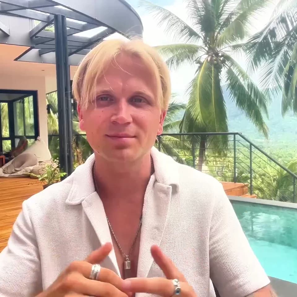 Leon Schäfer lächelt vor Palmen und einem Pool
