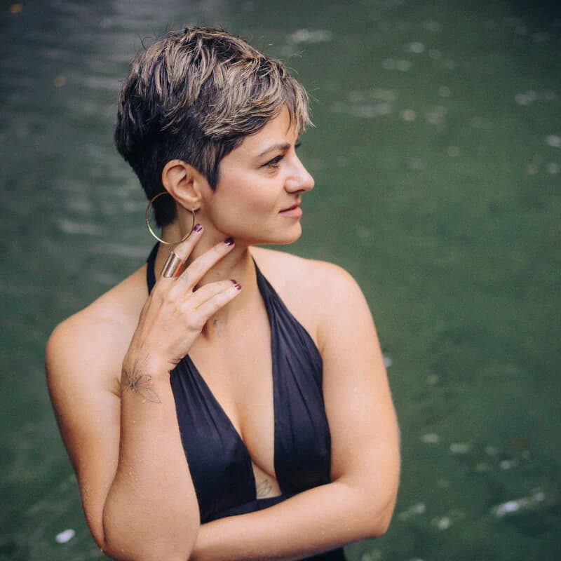 Neira steht in einem schwarzen Kleid vor ruhigem Wasser